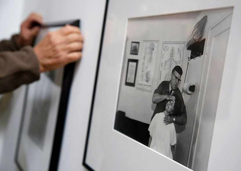  Burt Finger hangs one of four pieces by legendary documentary photographer Bill Owens at...