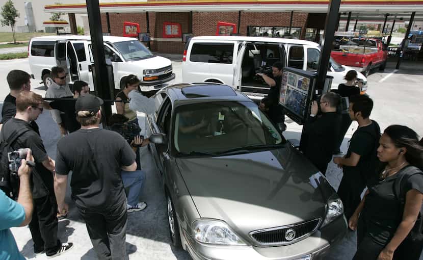 In this 2005 file photo, white vans block the path of a car as a camera crew, technicians...
