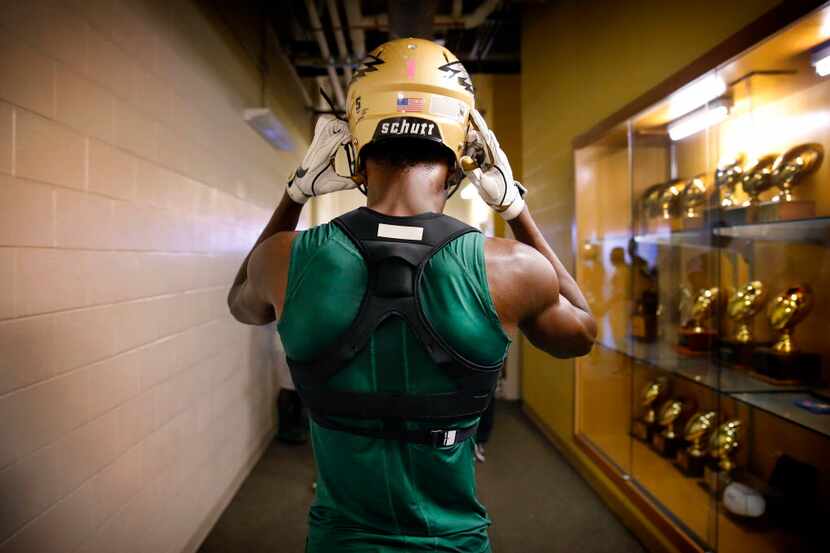 DeSoto High senior wide receiver Emmet Perry pulls on his helmet as he heads tot he field to...