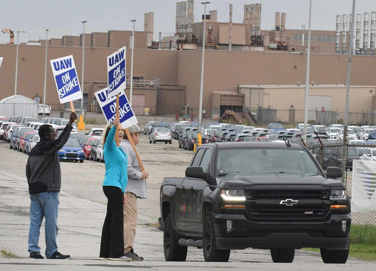 Debbie Gibson, in blue, and other UAW workers react as pickup truck driver honks the horn in...