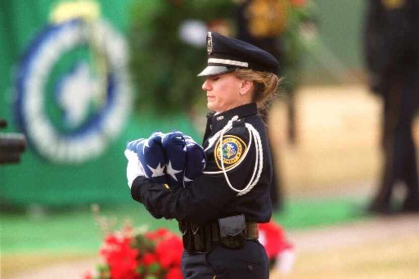 A police officer carried U.S. flags during the January 2001 funeral for Officer Aubrey Hawkins.