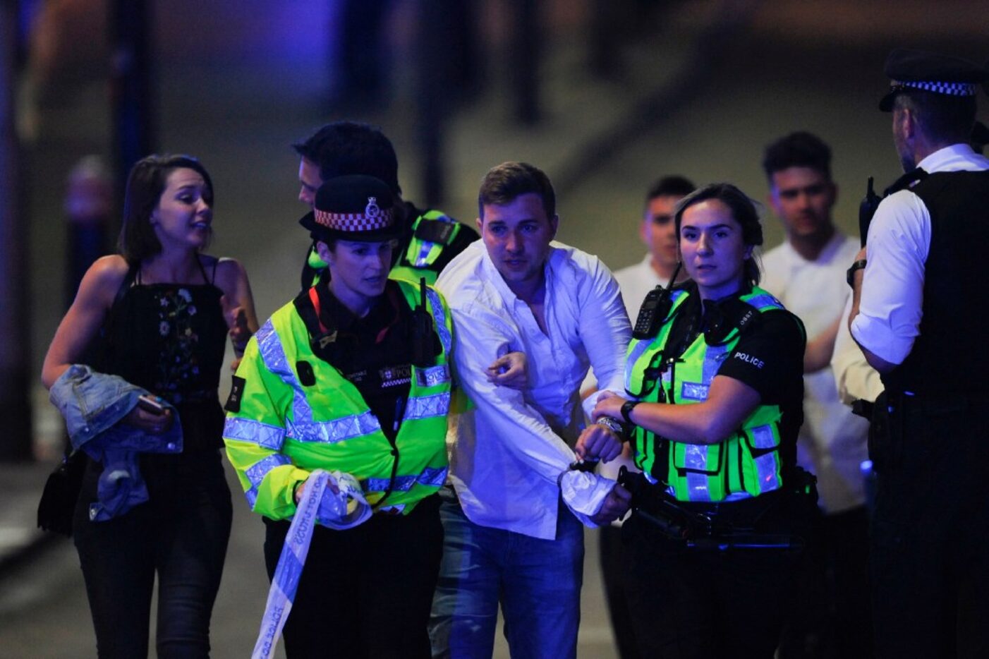 Police escort a member of public as they clear the scene of a terror attack on London Bridge...