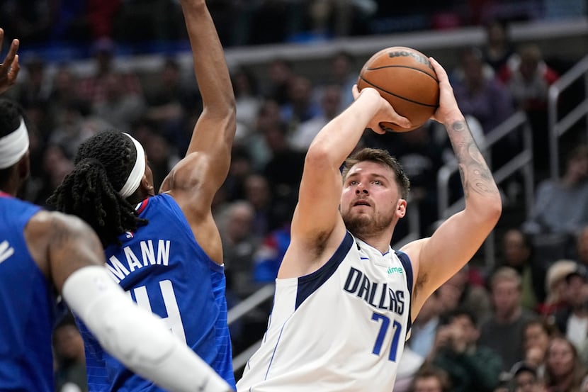 Dallas Mavericks guard Luka Doncic, right, shoots as Los Angeles Clippers guard Terance...