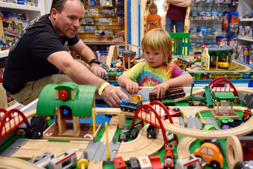 Ned Frost, 43, and son Julian Frost, 4, play with a train set while shopping inside The Toy...