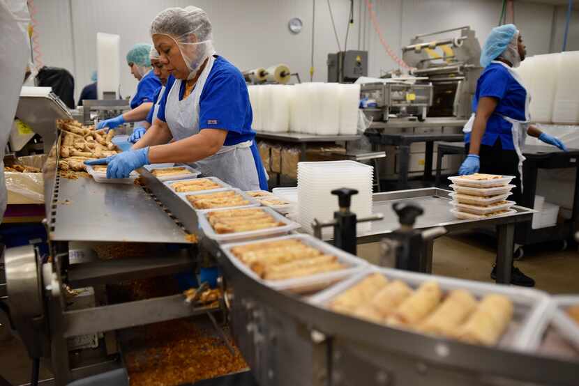 Employees of Van's Kitchen package egg rolls at the Van's Kitchen production plant.