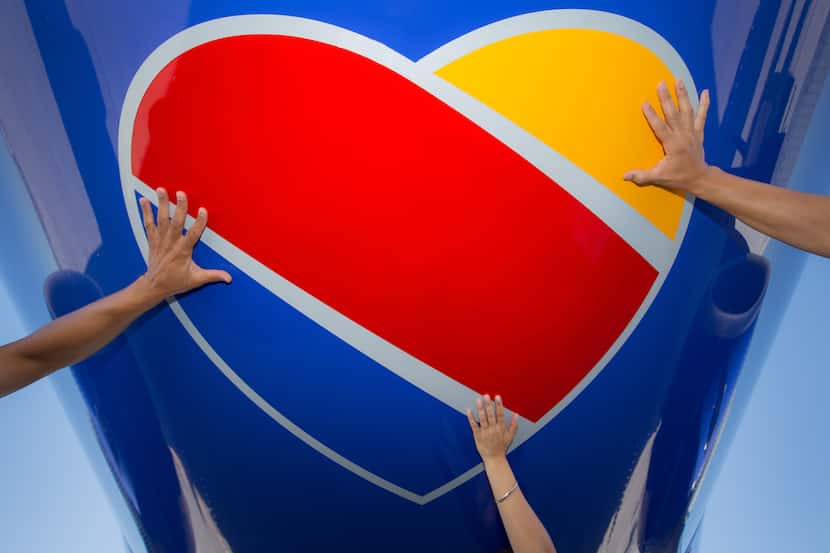 Hands touching the Southwest Airlines heart logo on the underside of a Boeing 737 jet.