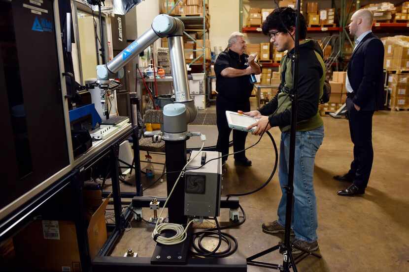 An All Axis Machining employee programs a robot with an OnRobot electric gripper to conduct...