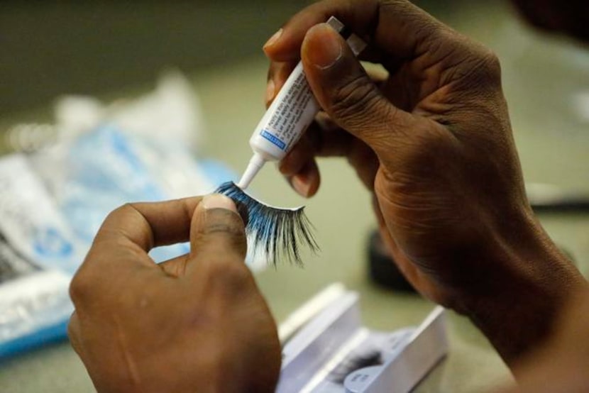 
Ivan Jones of Dallas applies false eye lashes as he transforms himself into Mrs. T Time as...