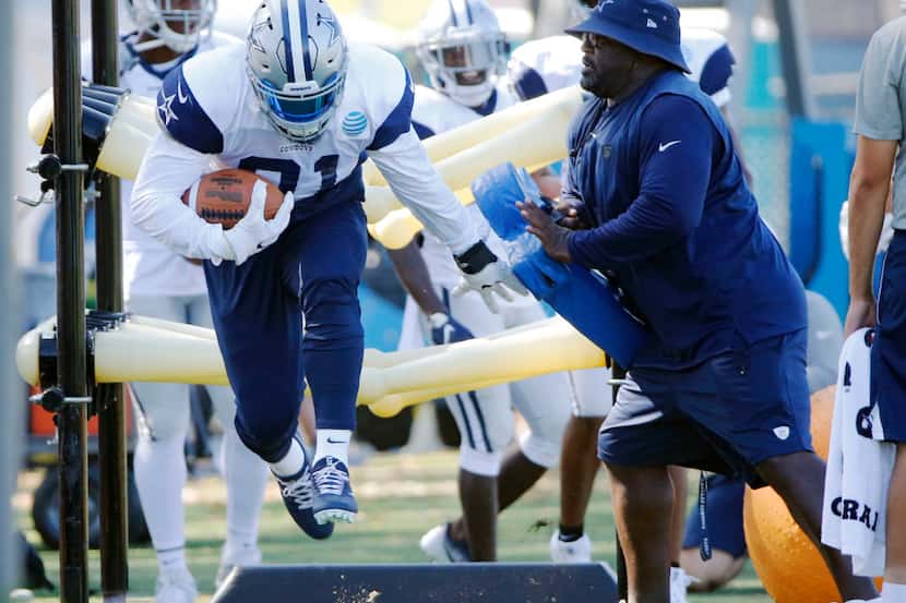 Dallas Cowboys running back Ezekiel Elliott (21) runs through a drill as running backs coach...