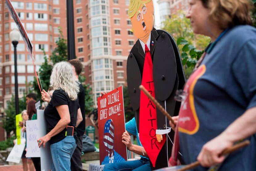 Demonstrators holds placards as others wait to enter the Albert V. Bryan U.S. Courthouse in...