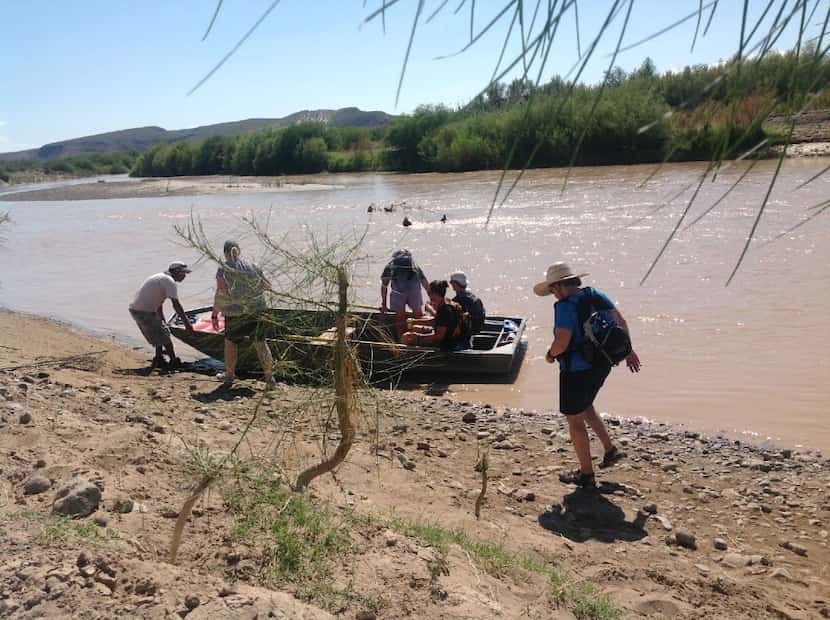 Tourists board the ferry on the banks of the Rio Grande after visiting the small town...