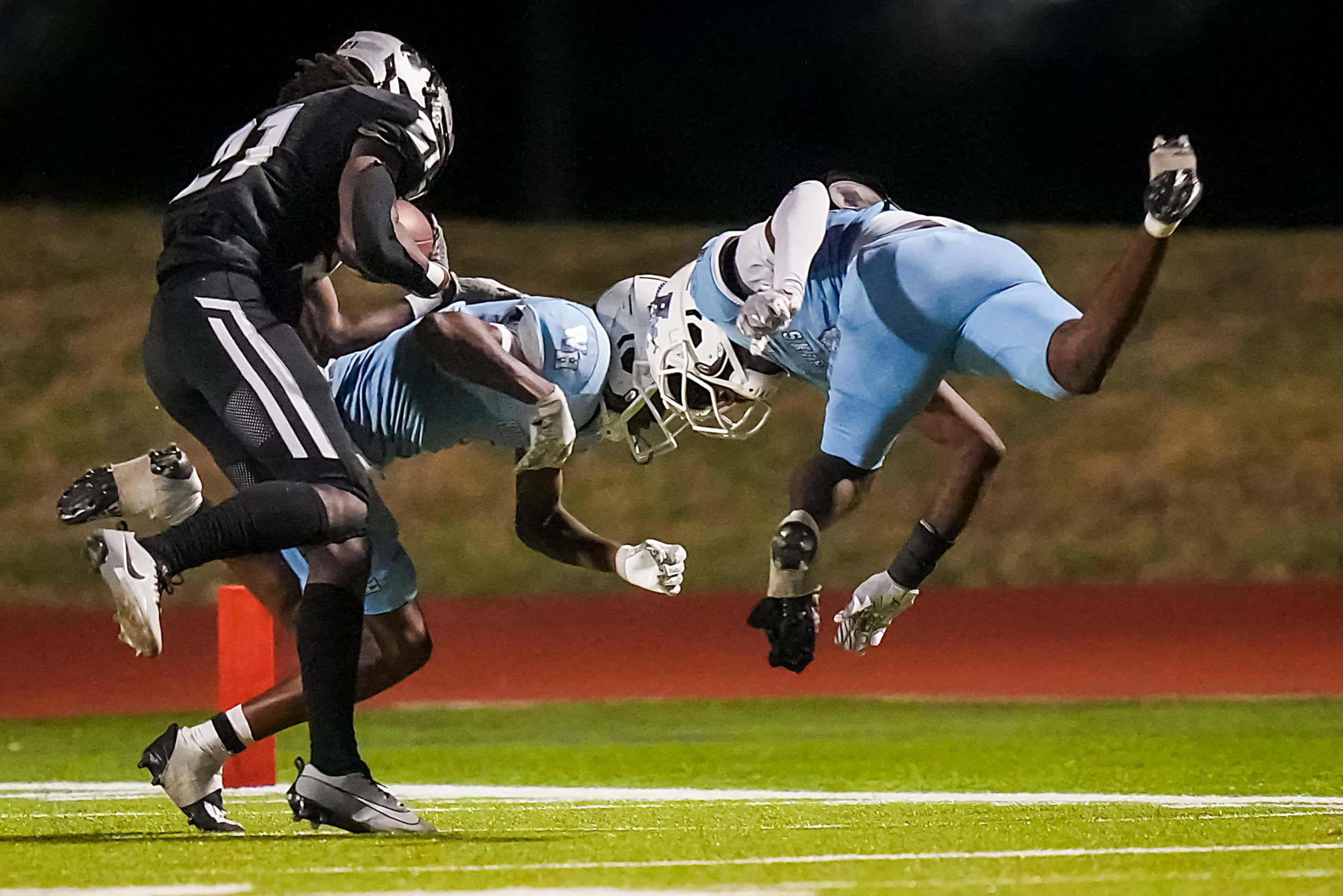 Panther Creek’s Donovan Webb (21) is brought down by Wilmer-Hutchins’ Taylor Pierce (7) and...