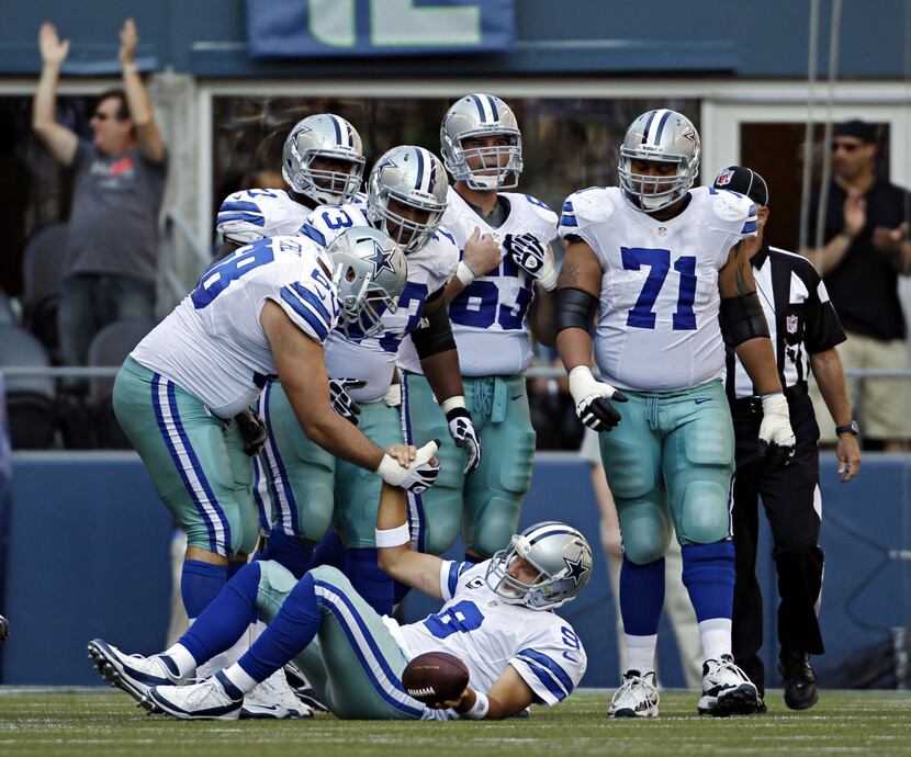 Dallas Cowboys tackle Doug Free (68) helps quarterback Tony Romo to his feet after he was...