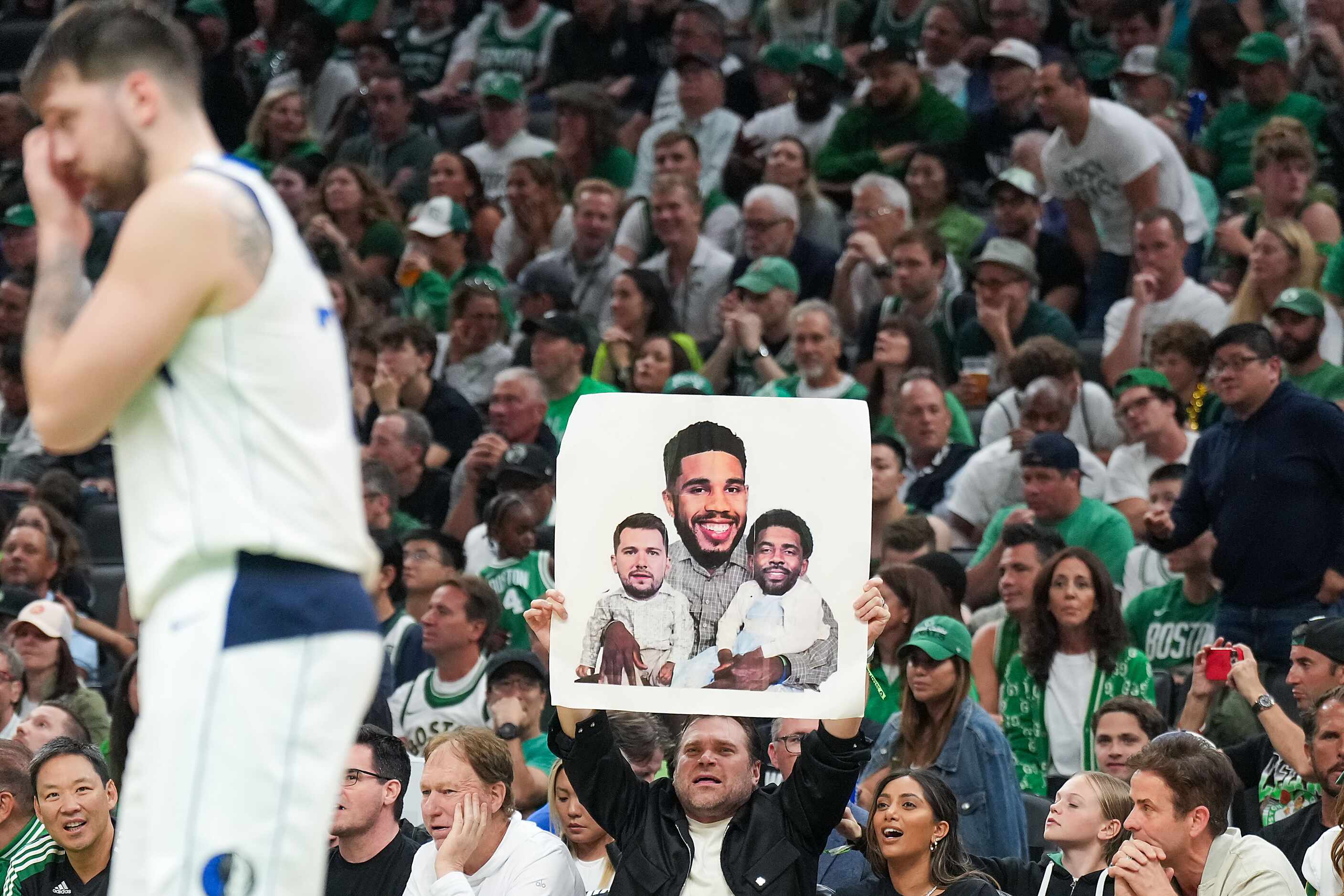 A Boston Celtics fan holds a sign taunting Dallas Mavericks guard Luka Doncic (left) and...