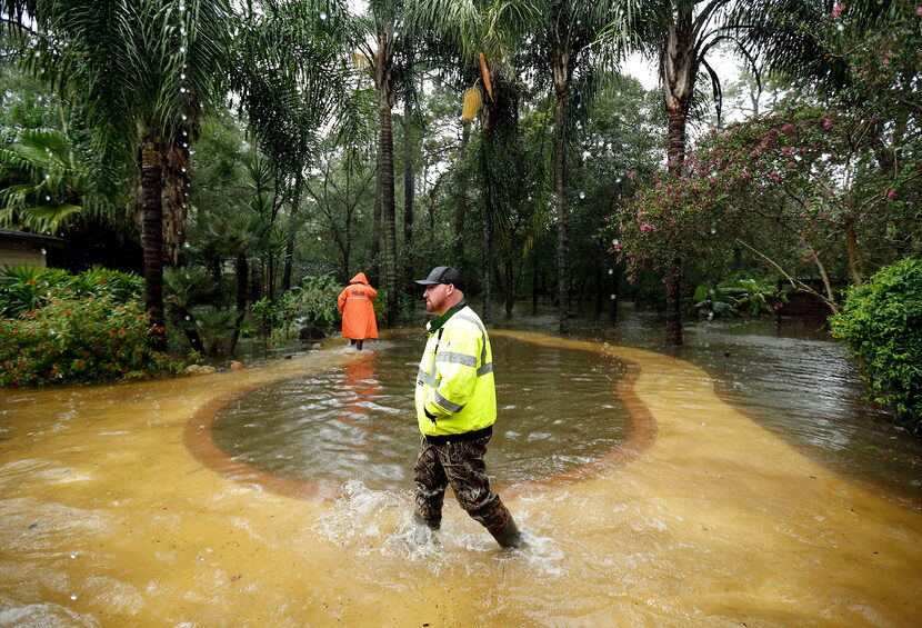 Volunteer Aaron Crump, center, and a Dickinson police officer search a Dickinson, Texas...