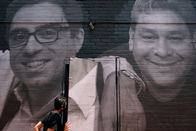 A woman steps through a door that is covered by a mural depicting American hostages and...