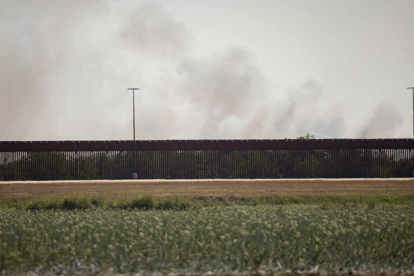 Smoke is seen over the US-Mexico border wall, following the end of a blockade by drivers in...