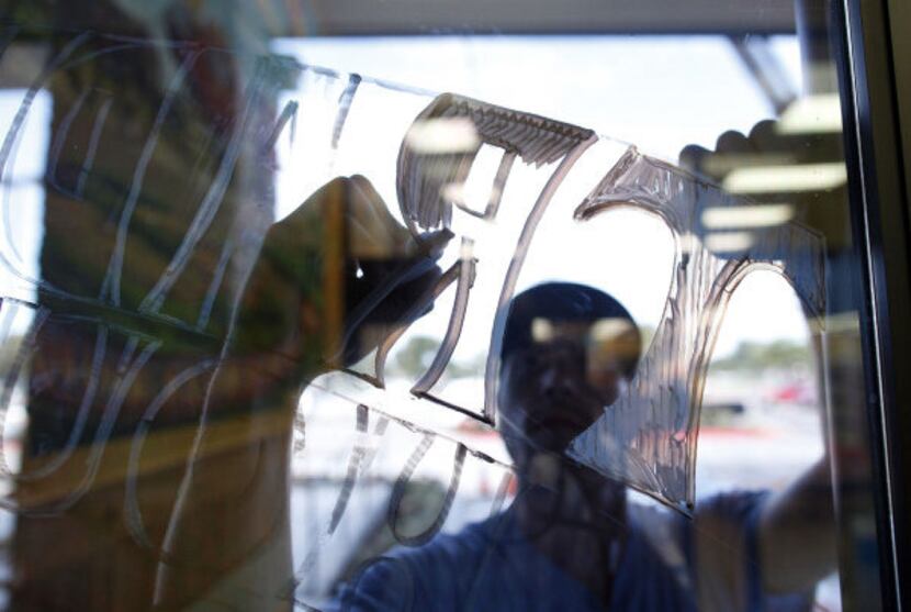 Lucas Weaverling works on a sign on the front door at Trader Joe's in Plano. The Plano...