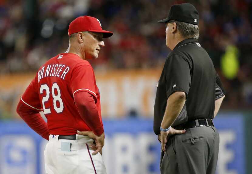 Texas Rangers manager Jeff Banister (28) talks with a first base umpire about a call against...