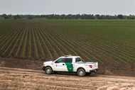 A Customs and Border Patrol officer patrols a portion of Frank Schuster's farm land along...