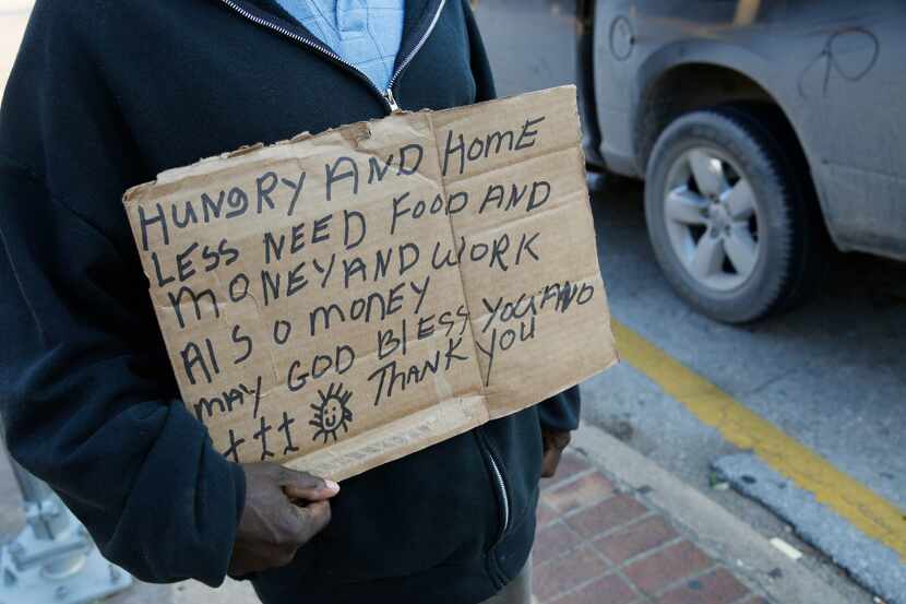 A homeless man solicits passing drivers for money at the intersection I-35E and Market...