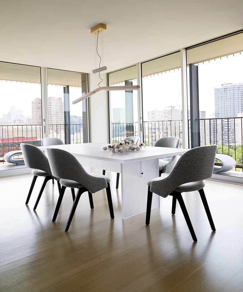 A dining room features a sleek, white table and views of downtown.