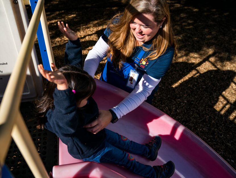 Teacher Alecia Gonzalez helps Natalia Lopez-Tafoya, 3,  down a slide on the playground on...