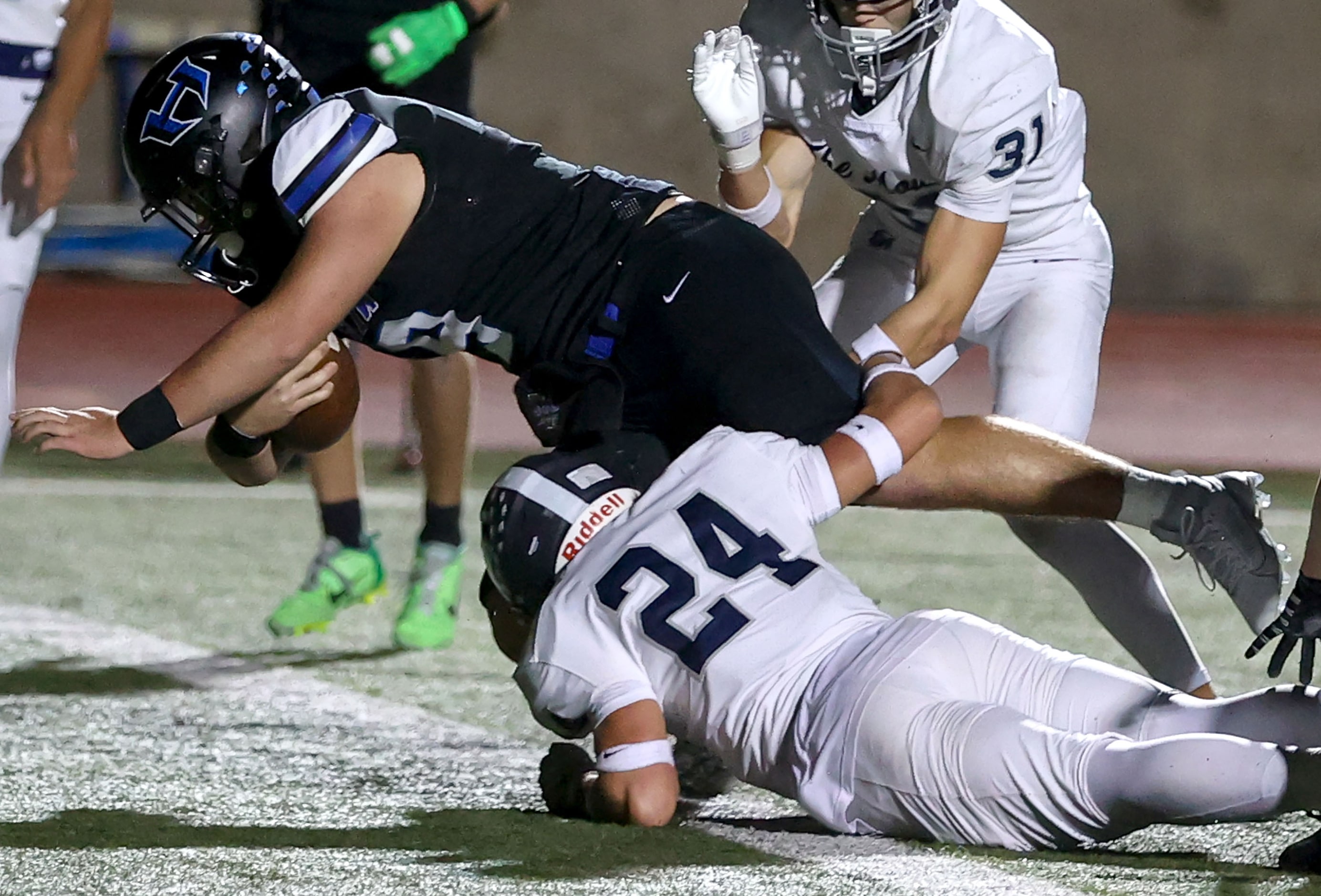 Hebron running back Antonio Dennis (9) dives over Flower Mound safety Slate Dettweiler (24)...