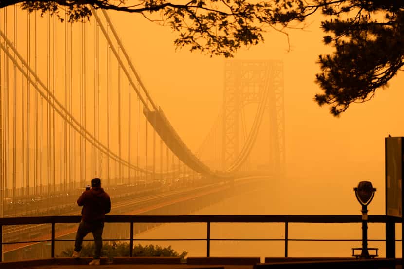 A man talked on his phone as he looked through the haze at the George Washington Bridge from...