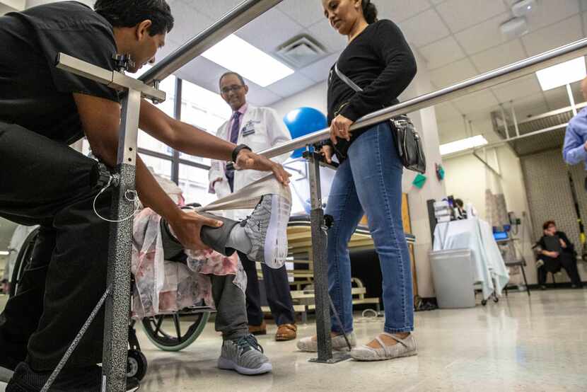 Physical therapist Binu Aramath (left) helps Hareg Wolde's mother as neurologist Dr. Mehari...