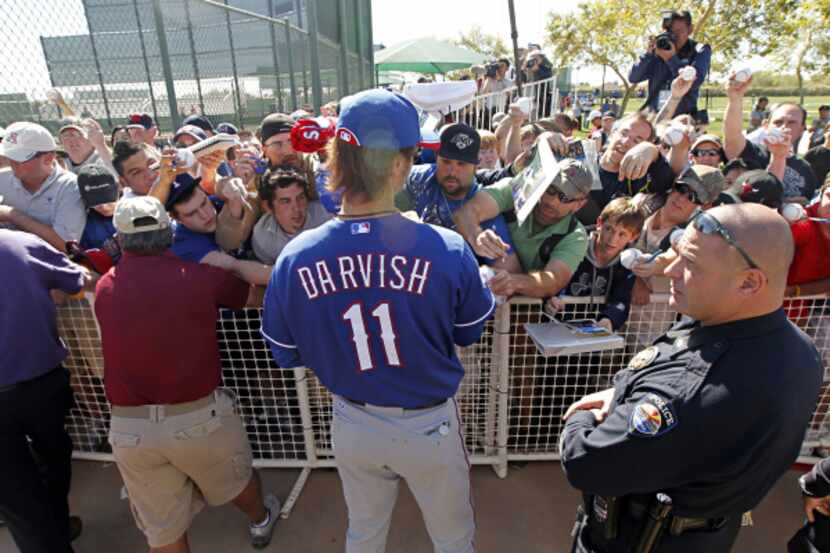 Fans clamor for autographs from Texas Rangers pitcher Yu Darvish during spring training camp...
