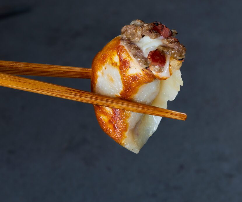 Bacon cheeseburger dumpling held with chopsticks from Brooklyn Dumpling Shop.