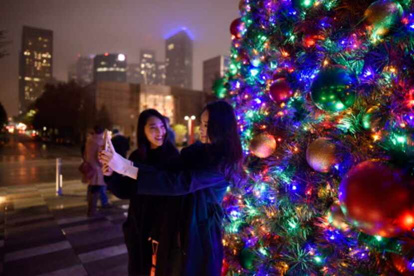 Eunji y Yegi Lee, de Dallas, se hacen un selfie con el árbol navideño en Klyde Warren Park.
