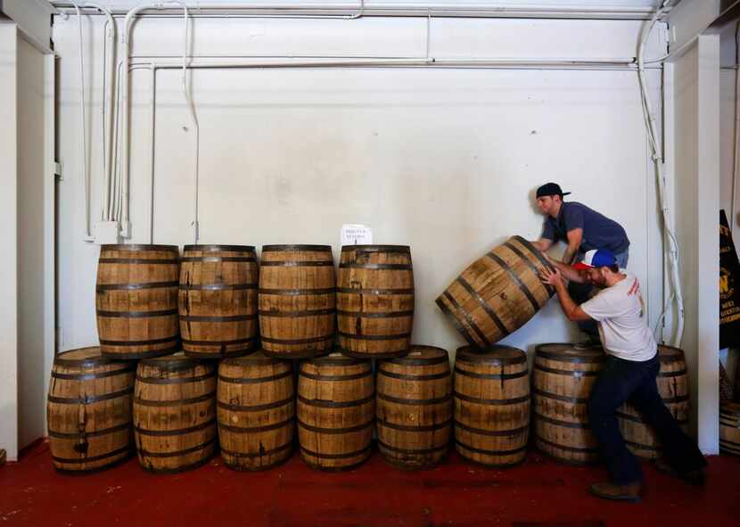 Tyler Doyle (top) and Chris Leurig  stack barrels of whiskey at the Witherspoon Distillery...