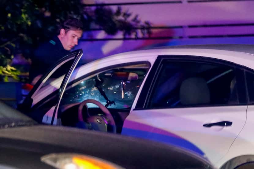 An officer inspects a vehicle that was involved in a Friday night shooting downtown.