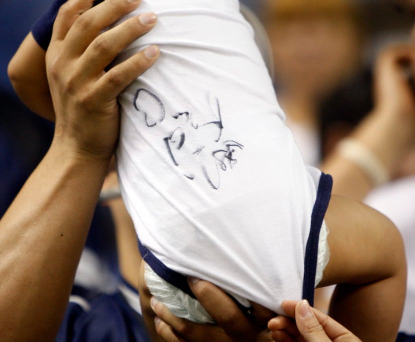 Dallas Cowboys fan Jason Flores  of Karnes City holds up his 9 month old son Jason James...