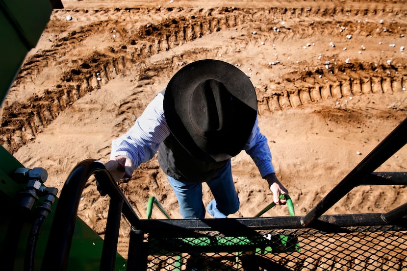 Matt Farmer climbs down from a cotton baler during the harvest at his farm in Lynn County.