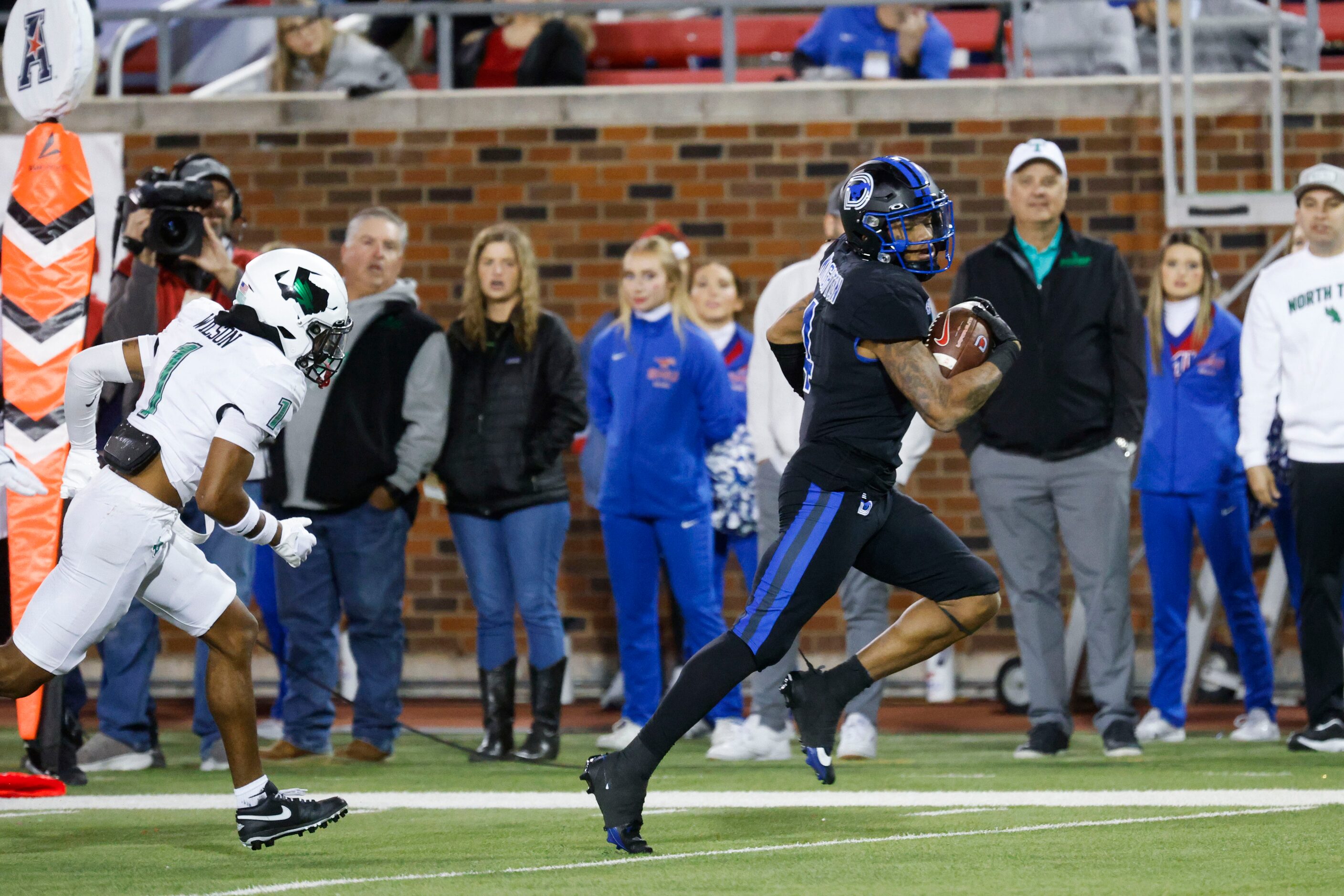 North Texas Mean Green safety Logan Wilson (left) runs behind Southern Methodist Mustangs...