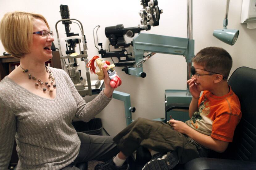 Dr. Stephanie Helm Fleming makes Askik Hossain, 7, laugh during an an eye exam at the Low...