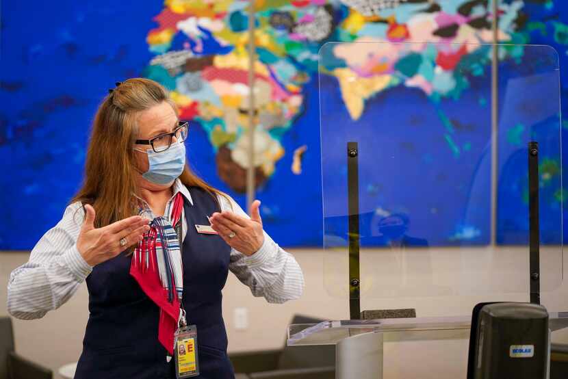 Tracy Burrell works behind a plexiglass screen at the American Airlines Admiral's Club...