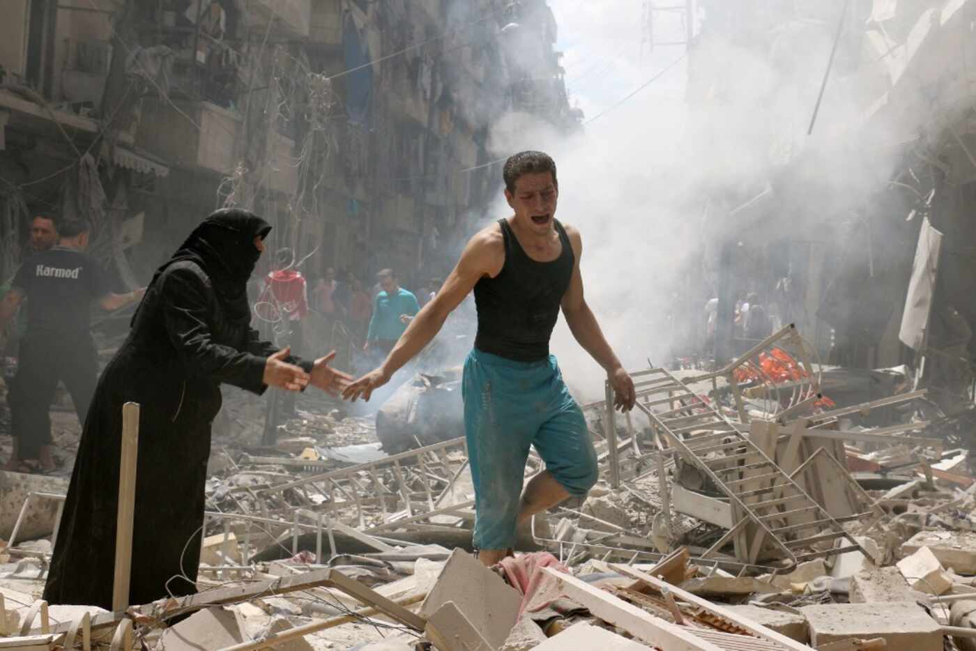 People walk amid the rubble of destroyed buildings following a reported air strike on the...