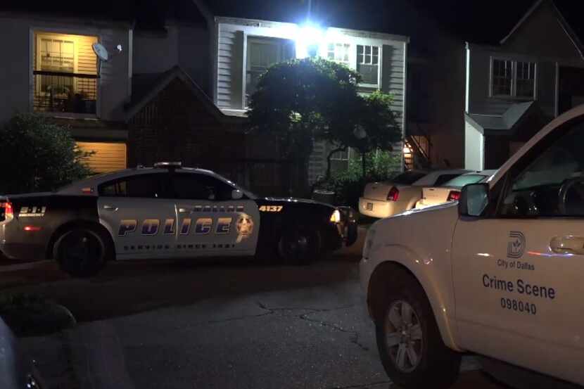 Dallas police vehicles sit outside an apartment complex where a man was shot trying to break...
