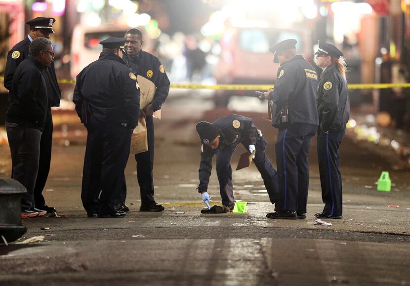 A crime scene technician collects clothing from the street as New Orleans Police investigate...