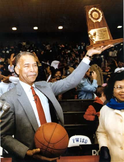 Fort Worth Dunbar High School coach Robert Hughes holds up the trophy presented to him for...