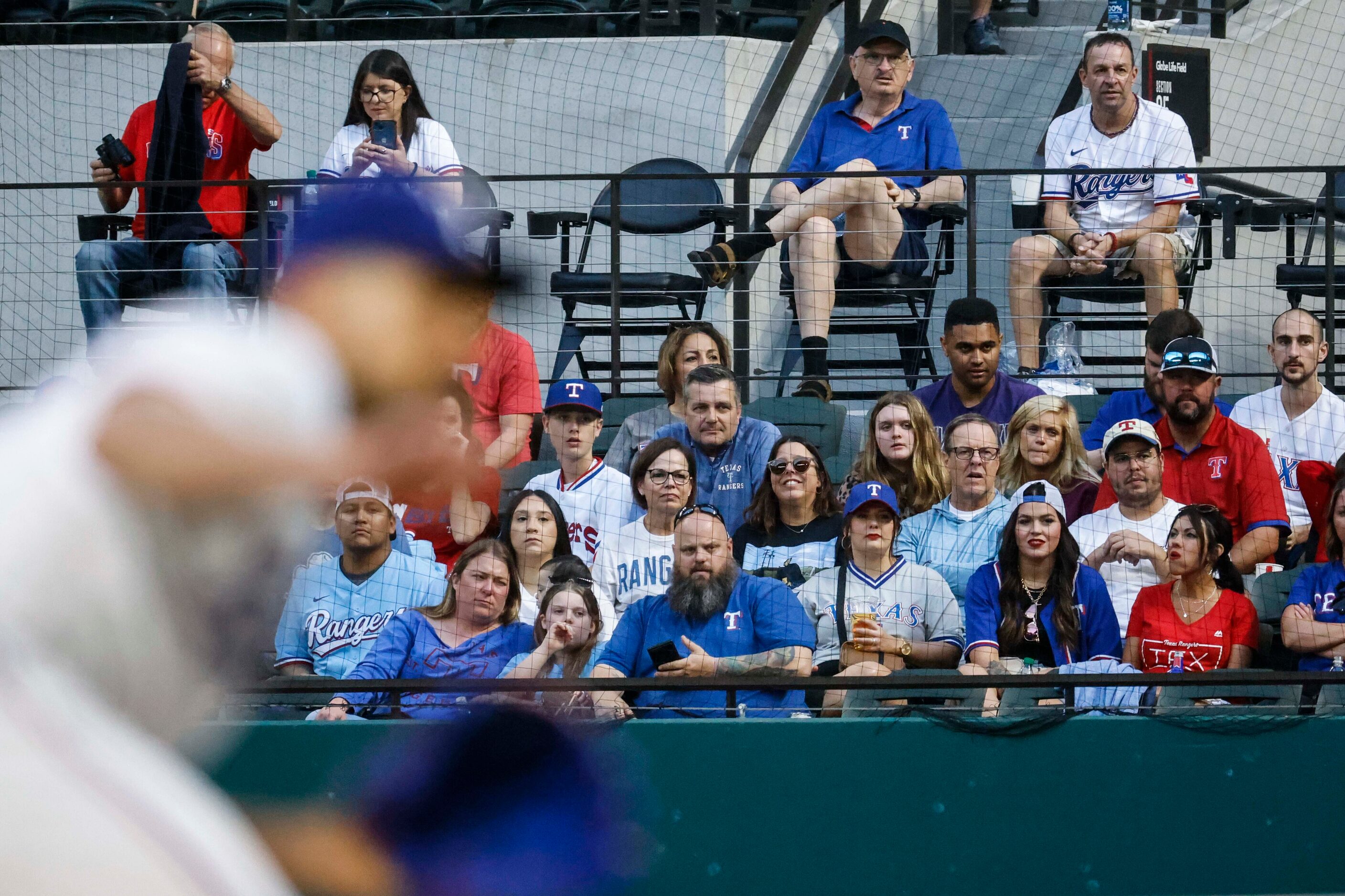 Fans watch as Texas Rangers starting pitcher Nathan Eovaldi throws during the third inning...