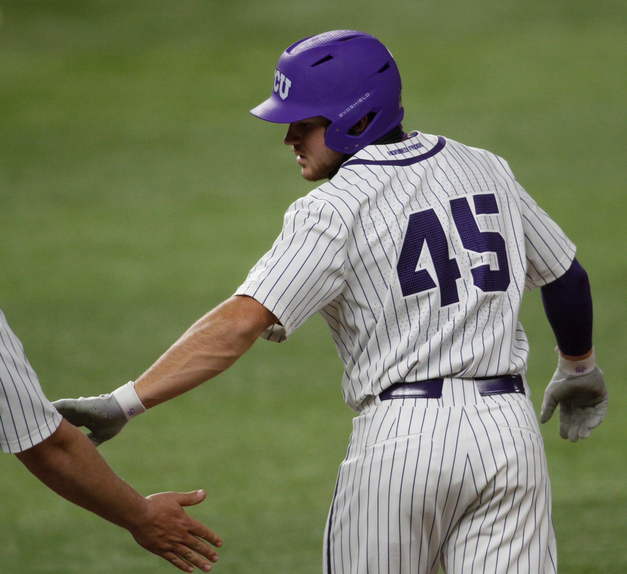 TCU outfielder Luke Boyers (45) reaches back to exchange a "low five" with the first base...