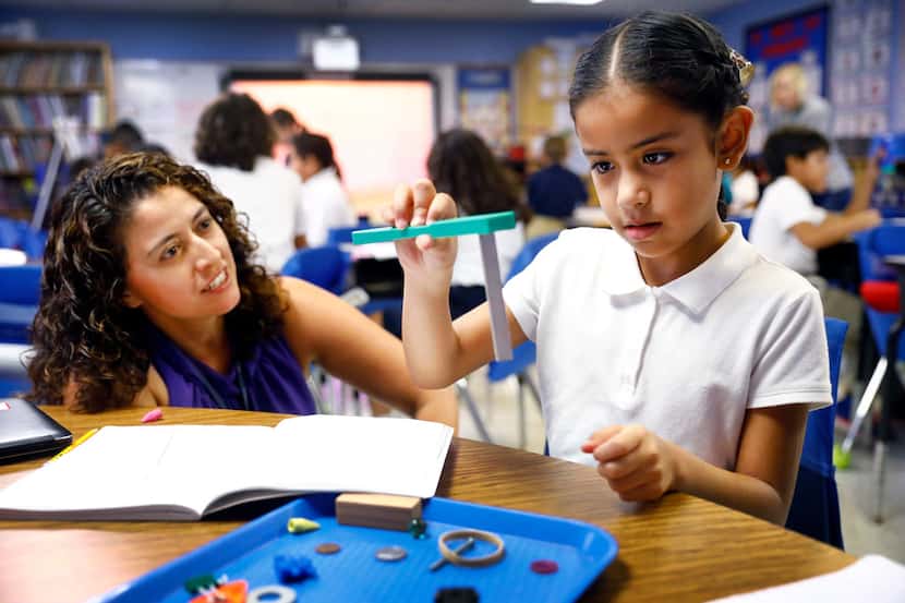 Third grader Jaime Tobon looks at the power of a magnet as her dual language science teacher...