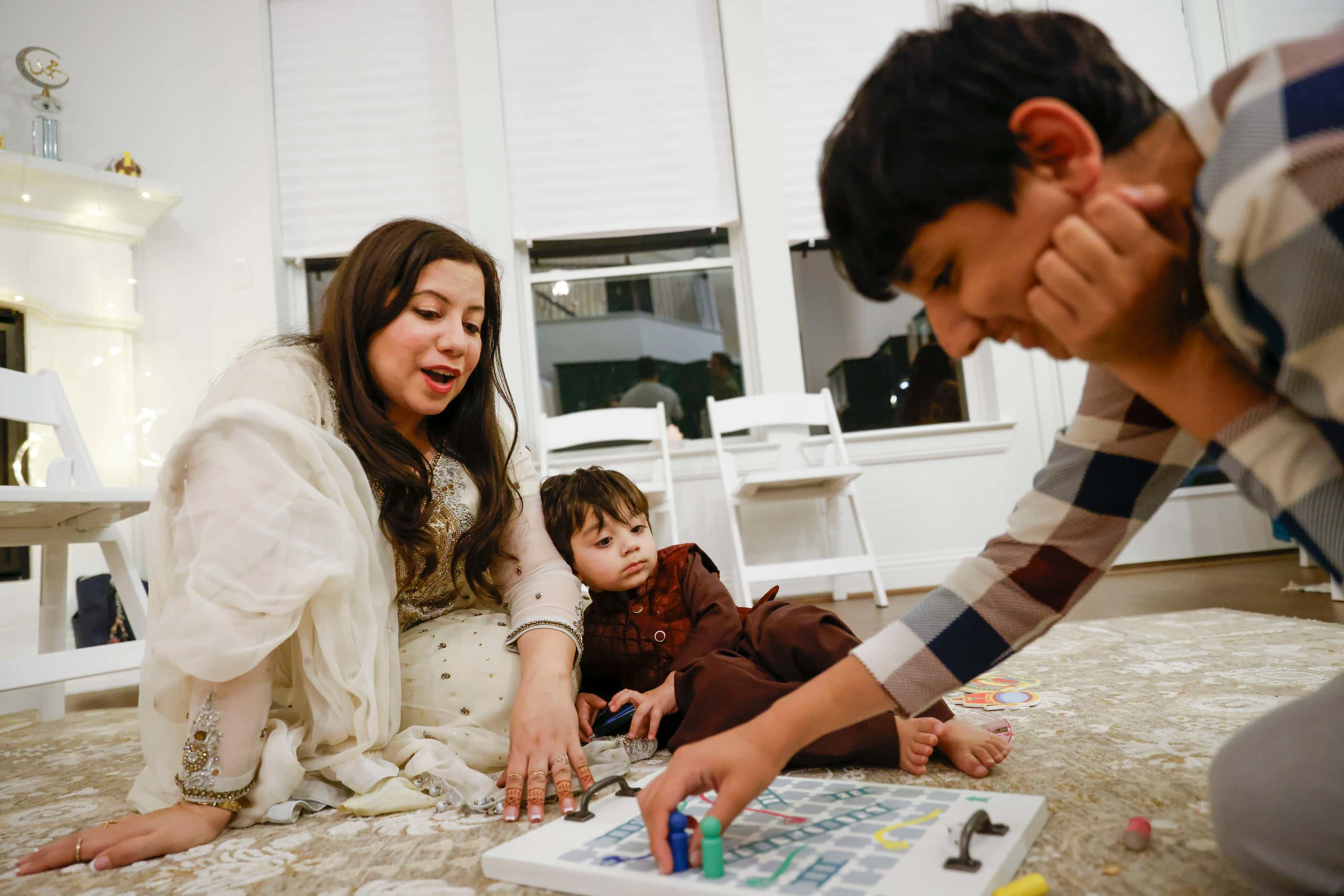 Aisha U-Kiu (left) reacts while playing a board game with her nephew Shahmir Adeel, 2,...