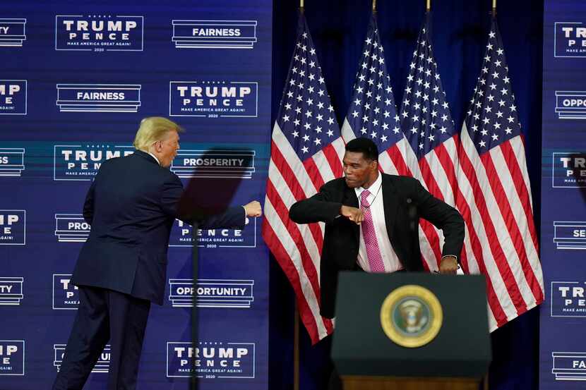 President Donald Trump elbow bumbs with Herschel Walker during a campaign rally, Friday,...
