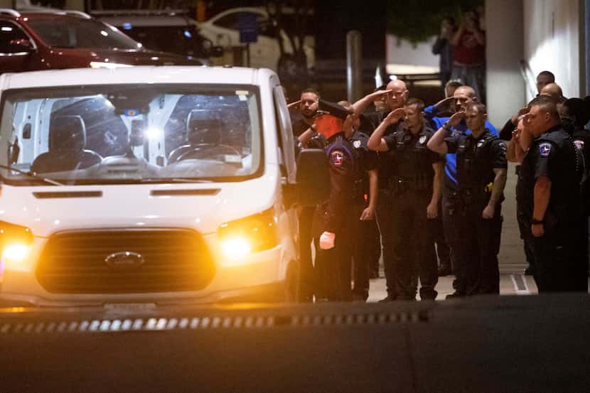 Officers salute as a Mesquite police officer’s body is loaded into a van outside Baylor...